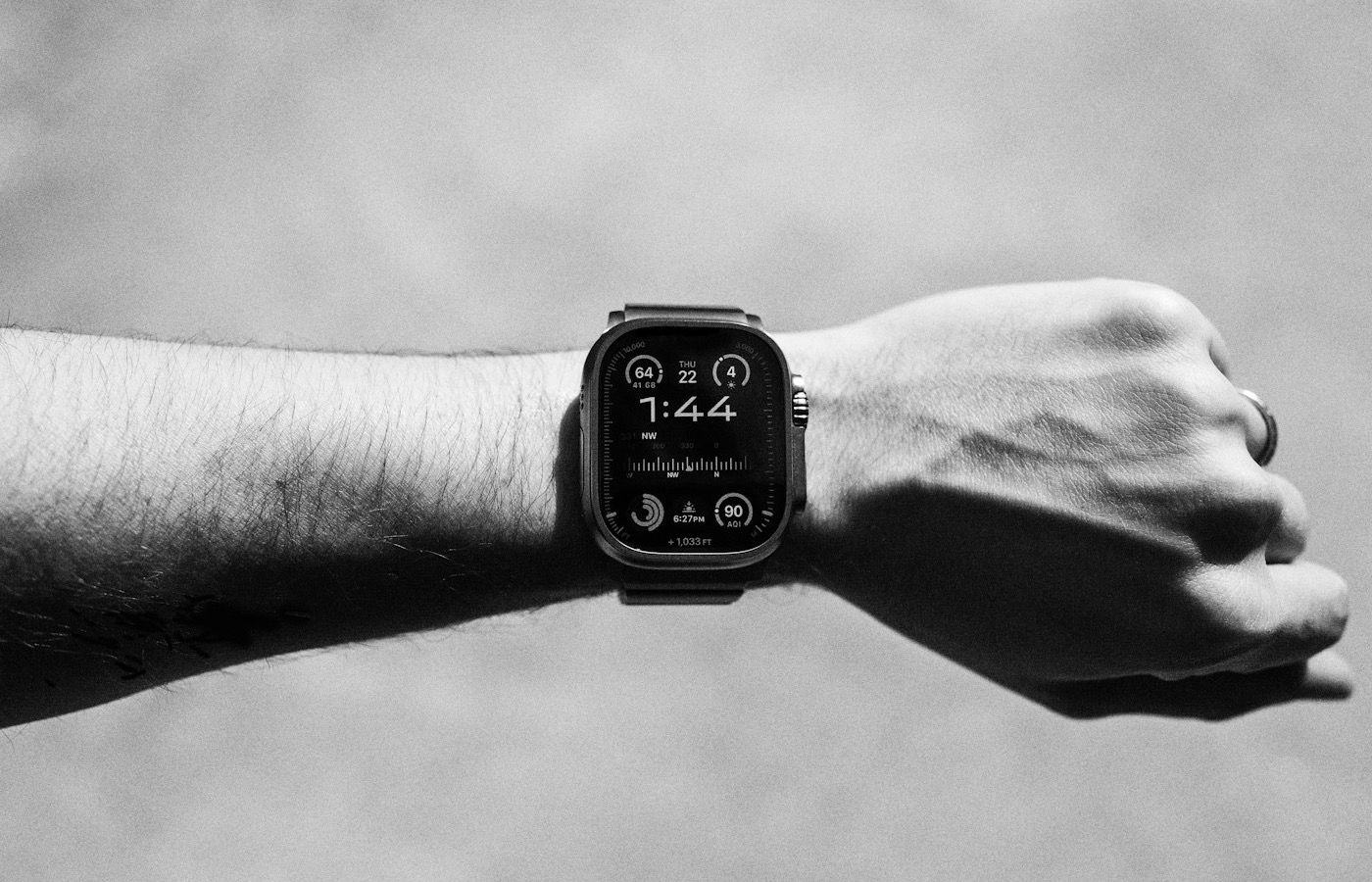 An Apple Watch Ultra on a clenched wrist, its face showing activity rings and workout complications